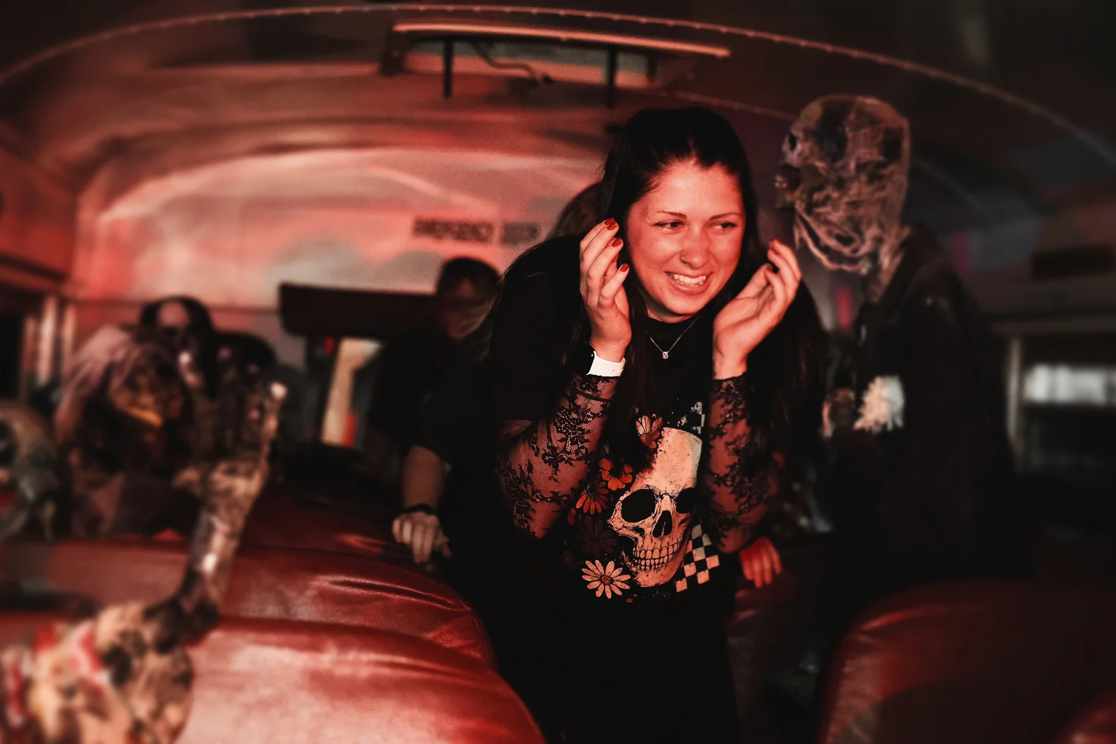 A guest laughs inside the Zombie Bus with a character behind her.