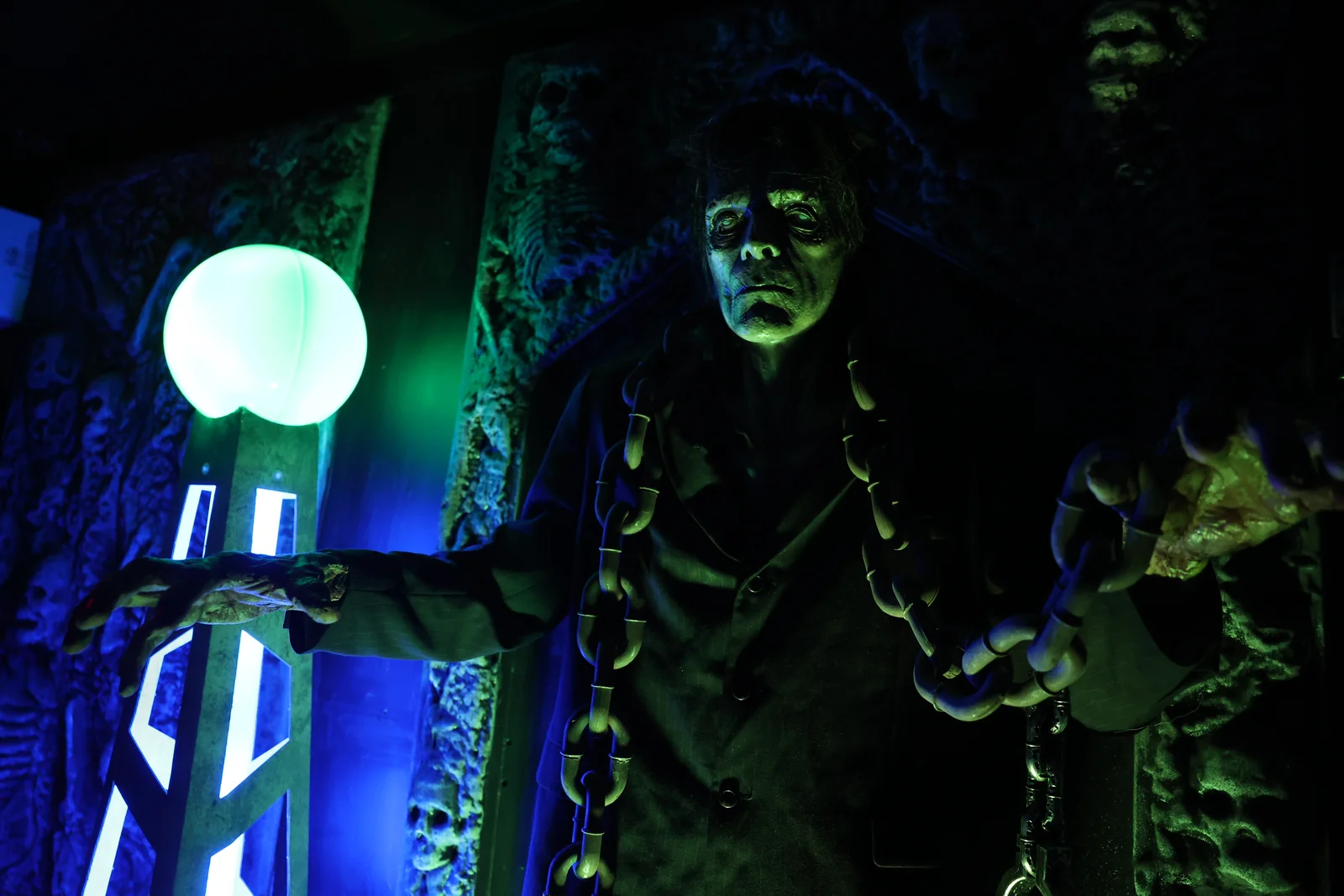 A green-lit character reaches out beside a glowing orb.