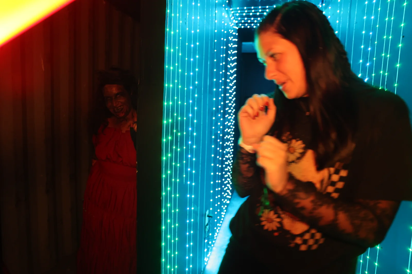 A guest reacts to a scare beside blue lights inside the haunt.